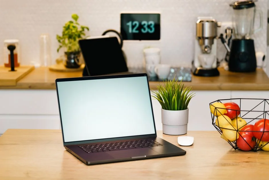 An older woman is seated on a yoga mat in a chic living room, using a laptop.